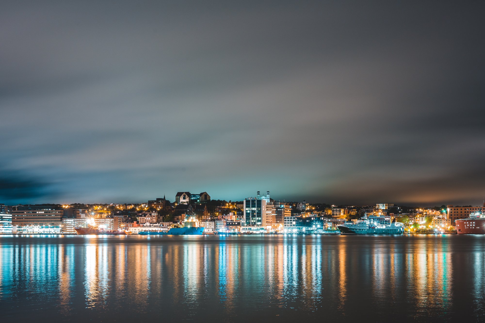 Photo by Erik Mclean: https://www.pexels.com/photo/cloudy-night-sky-over-illuminated-coastal-city-and-harbor-4593510/