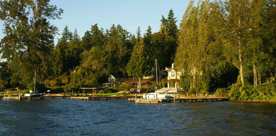 Image: Recreational property with cabin near lake, surrounded by trees and mountains.